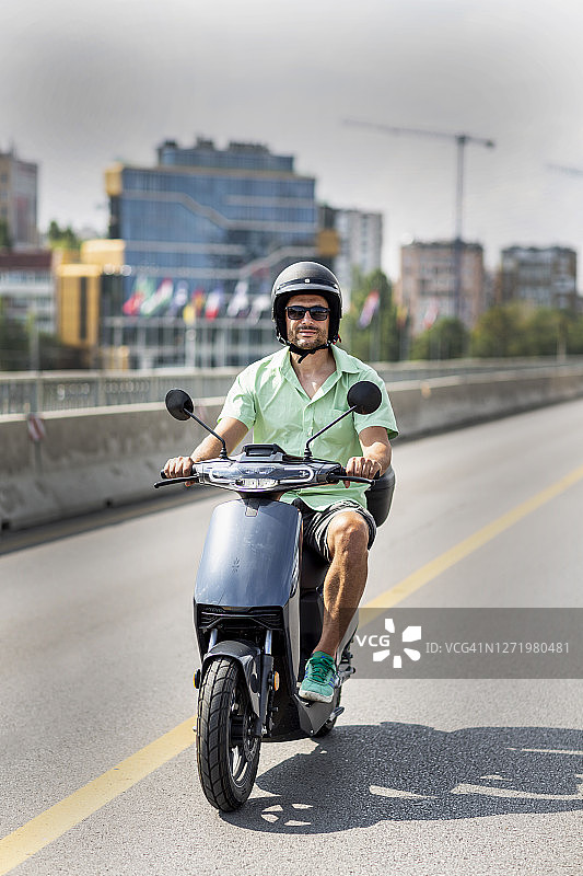 快乐和活跃的成熟男子驾驶电动车在城市图片素材