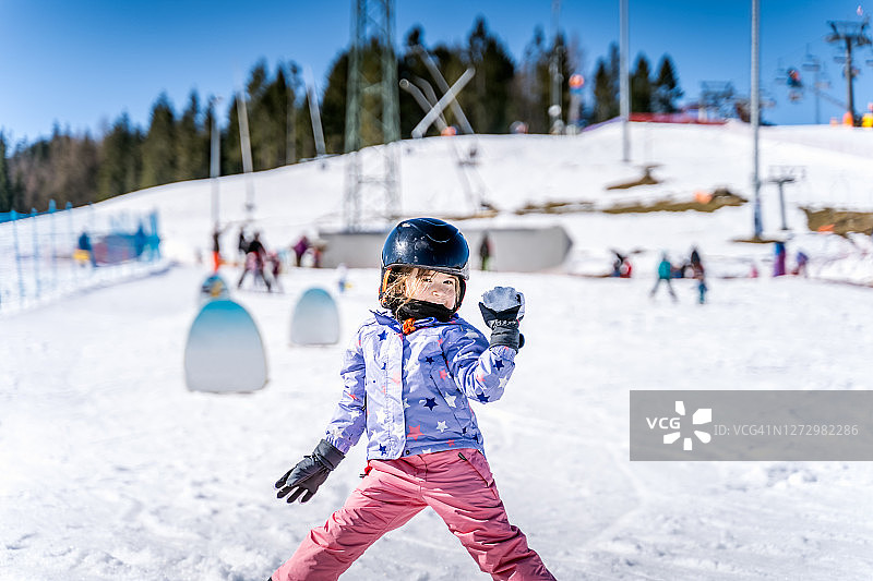 年轻快乐的滑雪女孩在打雪仗中扔雪球。图片素材