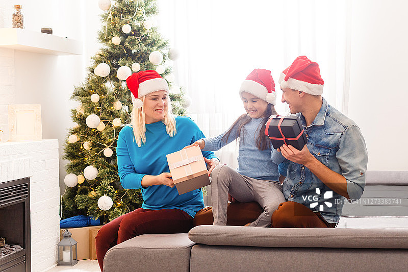 家庭，圣诞节，圣诞节，冬天，幸福和人的概念-微笑的家庭在圣诞老人助手帽子与许多礼物盒和孟加拉灯图片素材