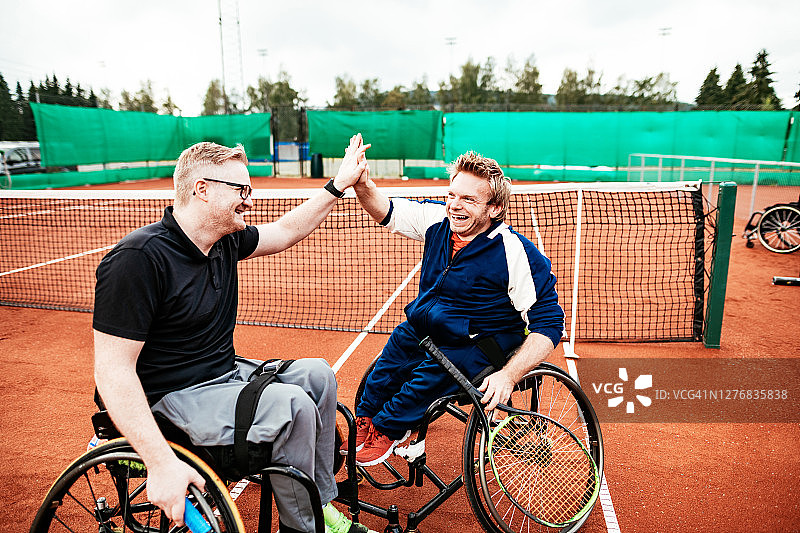 坐在轮椅上的男子在户外打网球——精神力量和健康克服身体上的障碍图片素材