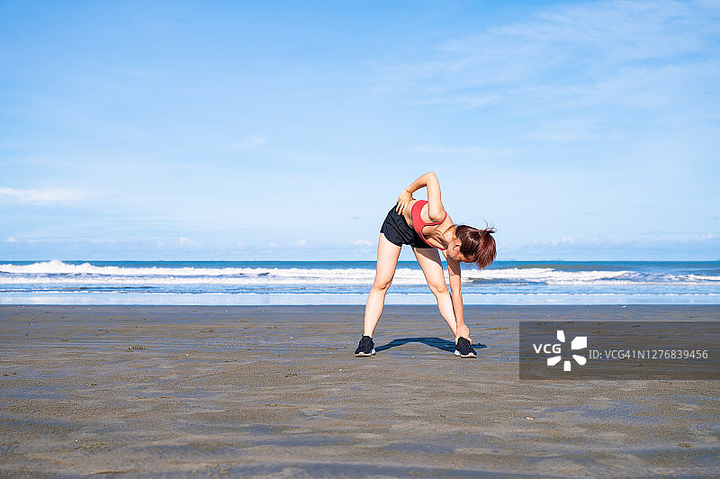 亚洲运动女性在早上在海滩上锻炼和伸展图片素材