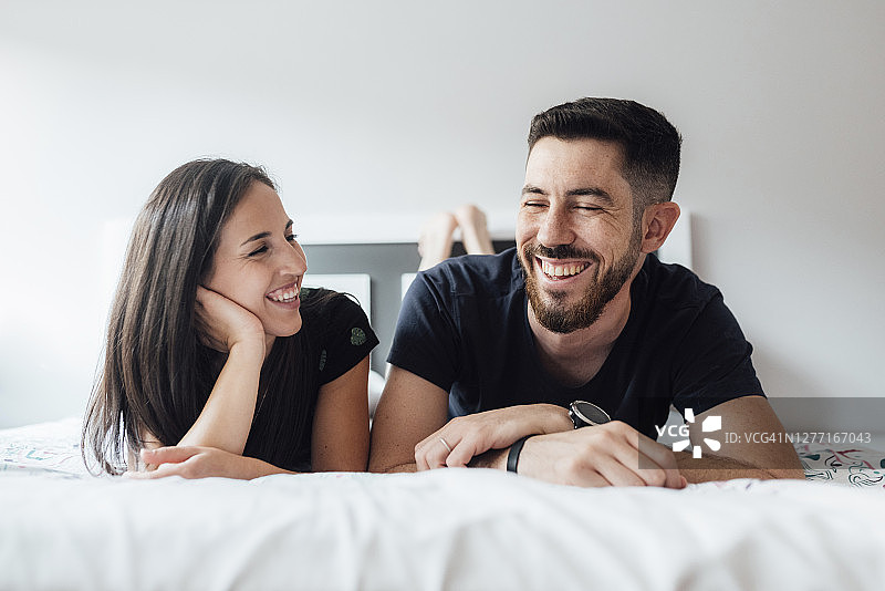 浪漫的微笑夫妇躺在前面的卧室在家里图片素材