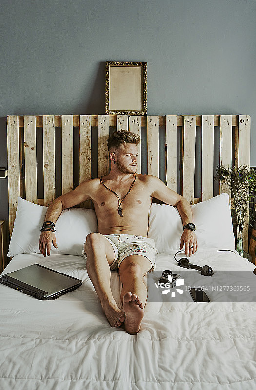 一名男子正在酒店的床上用笔记本电脑休息图片素材
