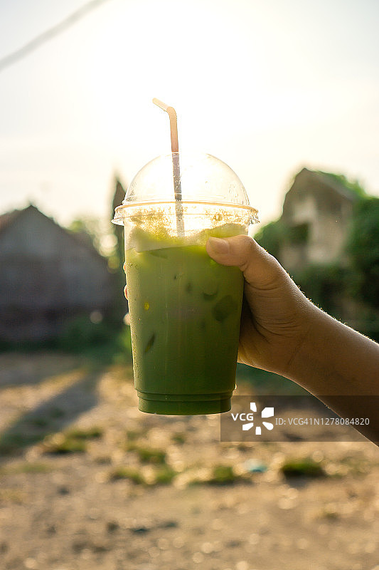 手拿绿茶冰与日落的景色图片素材