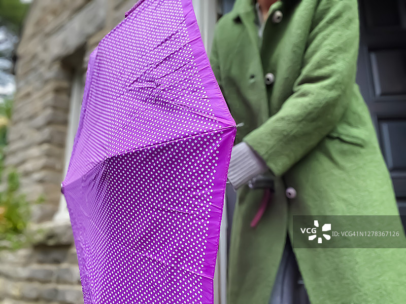 一位非裔美国妇女在一个细雨霏霏的秋日出门，穿着复古外套，带着一把雨伞图片素材
