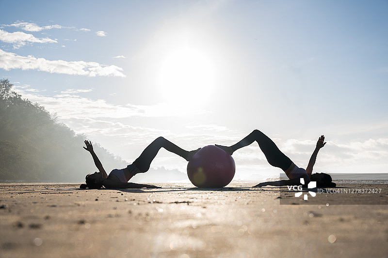 两个女人早上在海滩上练瑜伽图片素材