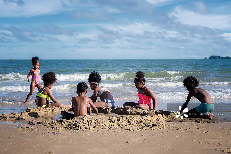 非洲裔美国儿童在海滩上玩沙子。图片素材