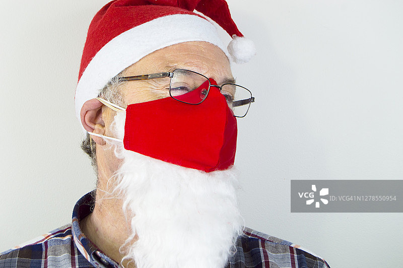 (2019冠状病毒病)戴圣诞老人帽、戴红色口罩的人员图片素材