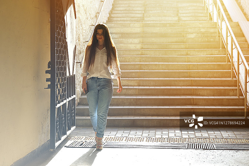 年轻美丽的女人走下台阶，微笑着来到地下道图片素材