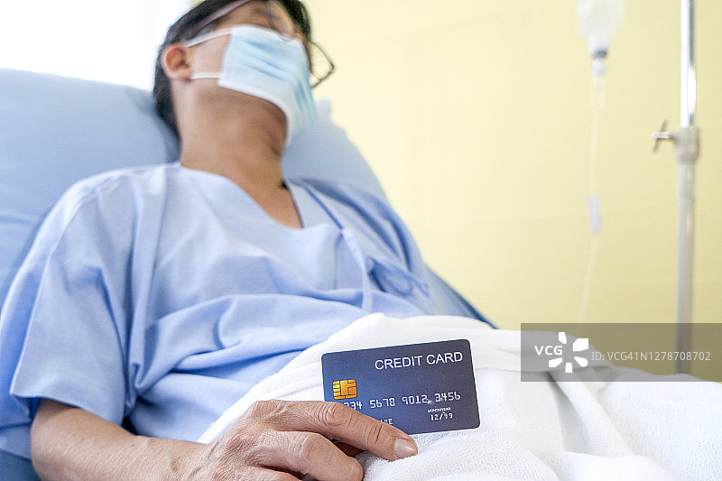 老亚洲病人显示信用卡与幸福和微笑的病人床上图片素材