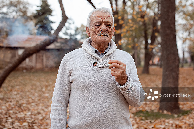 老人在秋季公园吸烟图片素材