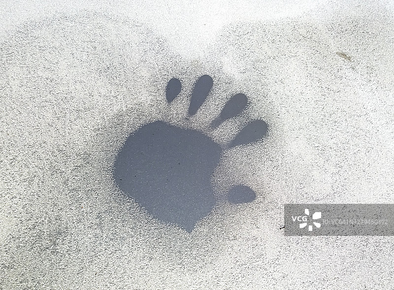 冰冻汽车挡风玻璃上的手印特写图片素材