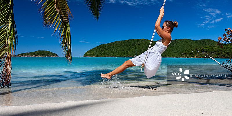 一个迷人的女人在加勒比海热带海滩荡秋千图片素材