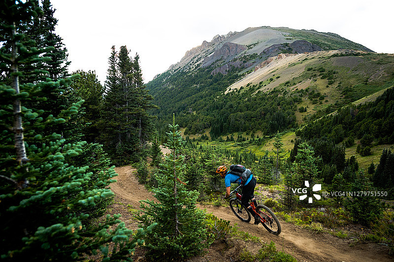 山地自行车手在高山的一条狭窄小道上骑行图片素材