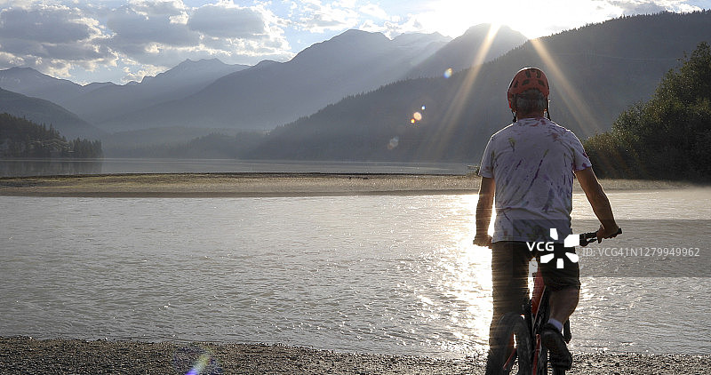 骑山地车的人在日出时骑到湖边图片素材