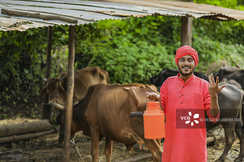 印度农民手里拿着奶瓶在奶牛场图片素材