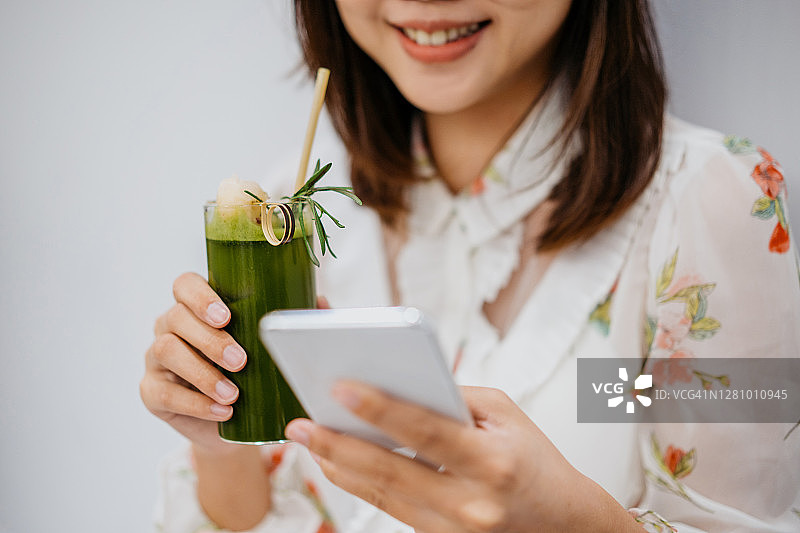 微笑的亚洲中国女性在咖啡馆使用智能手机图片素材