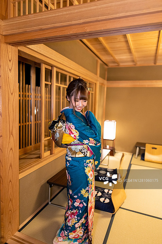 穿着Furisode和服的年轻女子站在日式旅馆的榻榻米房间里图片素材