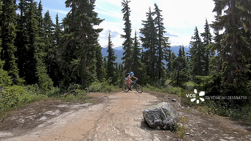 女性山地自行车骑上高山小径图片素材