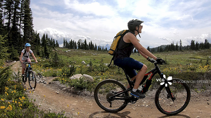 女性山地自行车手沿着高山小径骑行图片素材