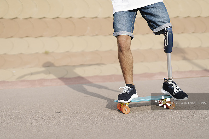 一个身体残疾的年轻人站在运动场的滑板上图片素材