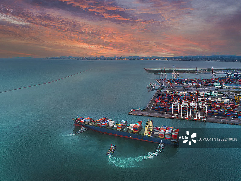 鸟瞰图拖船拖着集装箱货船到码头商埠的装卸码头进行商务物流、进出口、运输或货运。图片素材