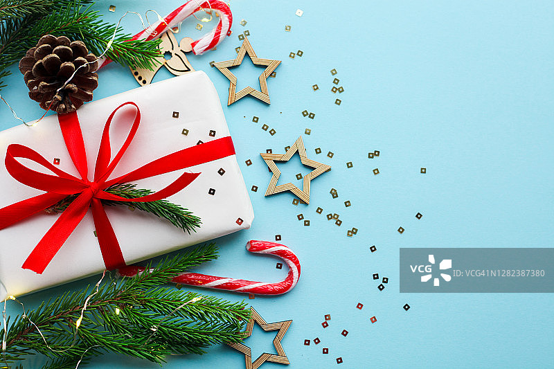 圣诞贺卡与糖果和松树冷杉绿色树枝在蓝色粉彩背景。圣诞彩灯、松果和天然植物装饰品。图片素材