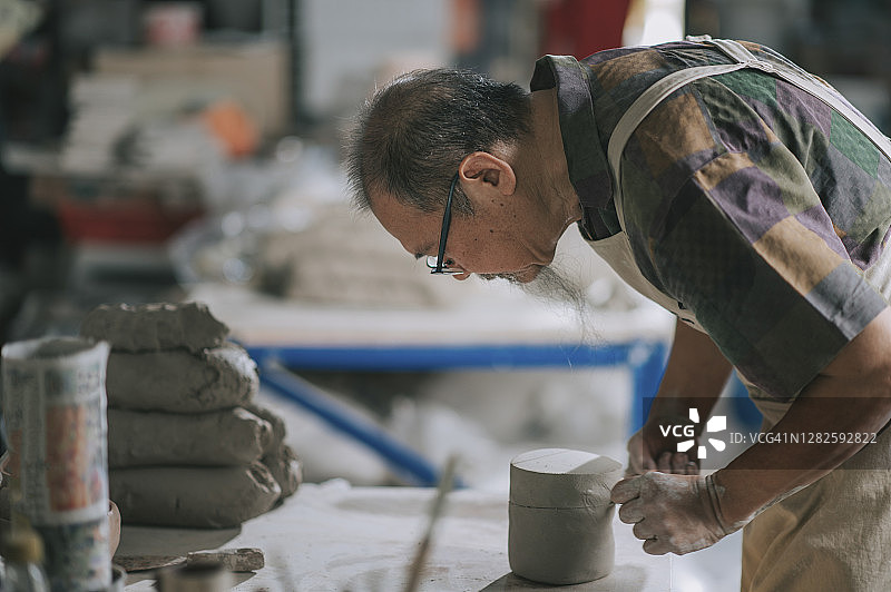 亚洲华人高级泥塑艺术家在他的工作室准备与粘土图片素材