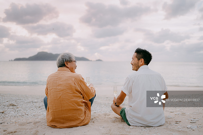 年老的父亲和儿子有一个很好的时间在海滩日落图片素材