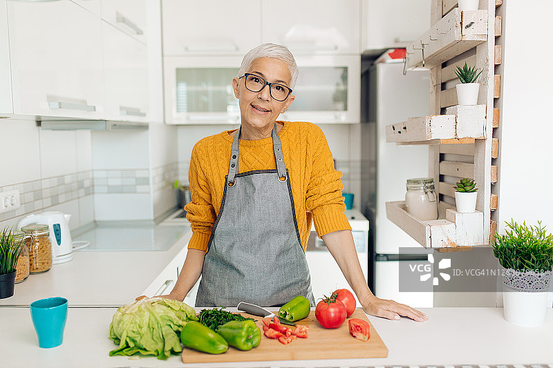一位年长妇女在厨房准备新鲜蔬菜的肖像图片素材