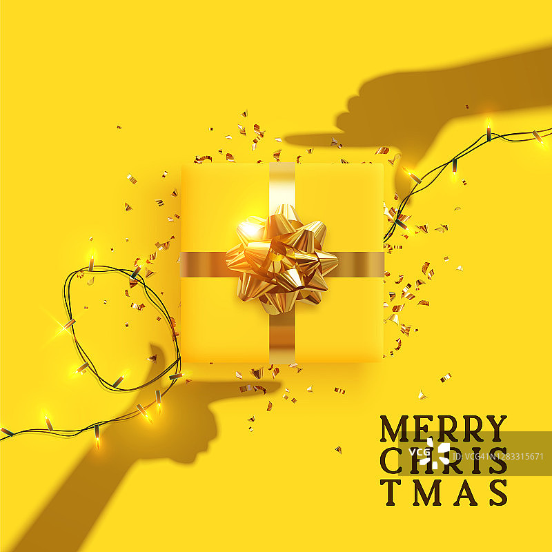 圣诞快乐，恭贺新禧。黄色背景与现实节日礼品盒。手的影子的效果是拿着礼物在焦点上。年轻女孩制作的相框手。圣诞礼物图片素材