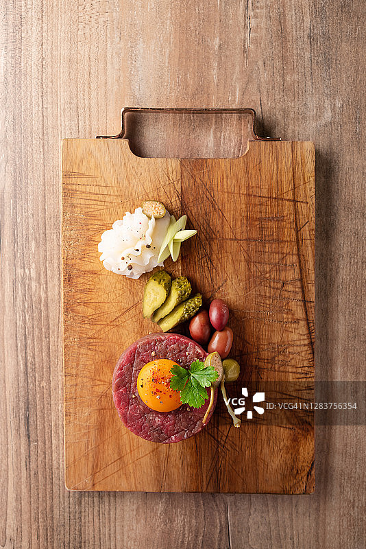 鞑靼牛肉牛排，鹌鹑蛋和香料放在木桌上图片素材