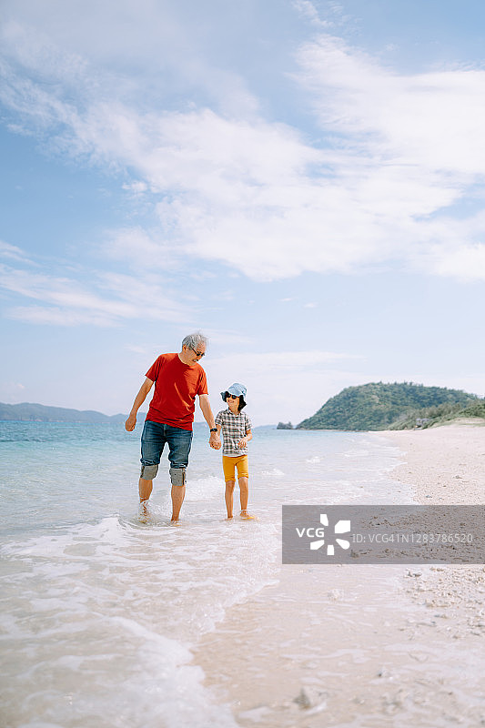 爷爷和孙女在日本的海滩上散步图片素材
