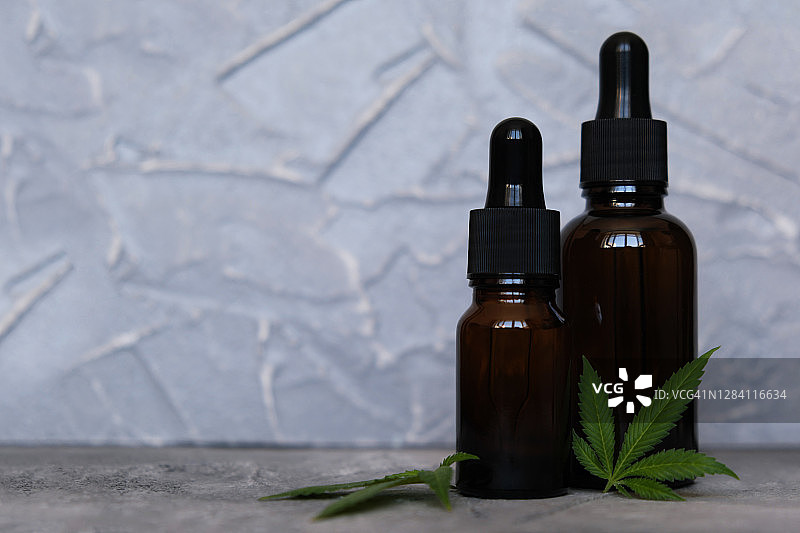 大麻CBD油提取物在罐子香草和叶在灰色背景图片素材