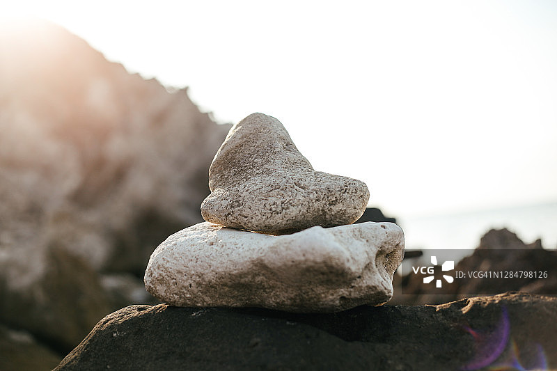 堆叠的石头，柔和的阳光和海滩和大海的背景图片素材