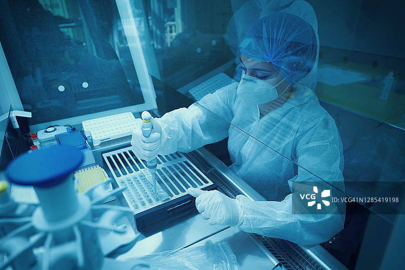 在通风柜后面的实验室工作的医务人员检测SARS-COV-2 pcr诊断试剂盒。图片素材
