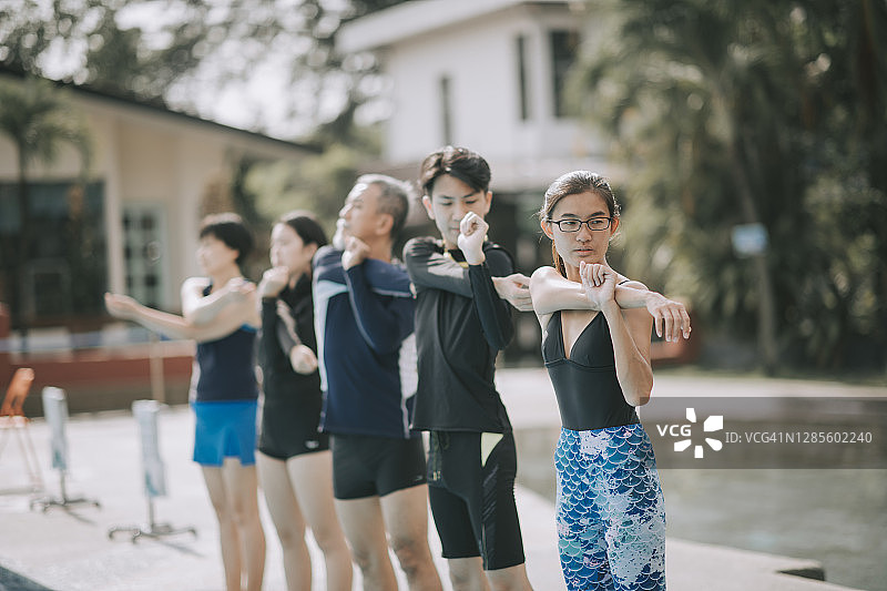 亚洲华人家庭早上在游泳池和教练做热身运动图片素材