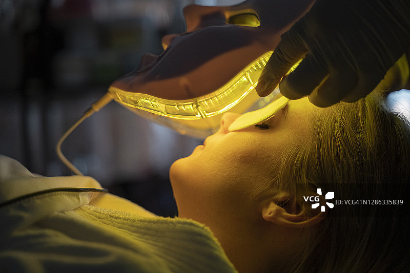 一位年轻女性的LED面膜再生治疗。图片素材