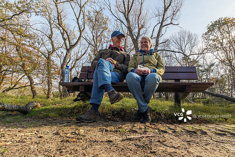 快乐的老年夫妇喝着咖啡，坐在一张木凳上图片素材
