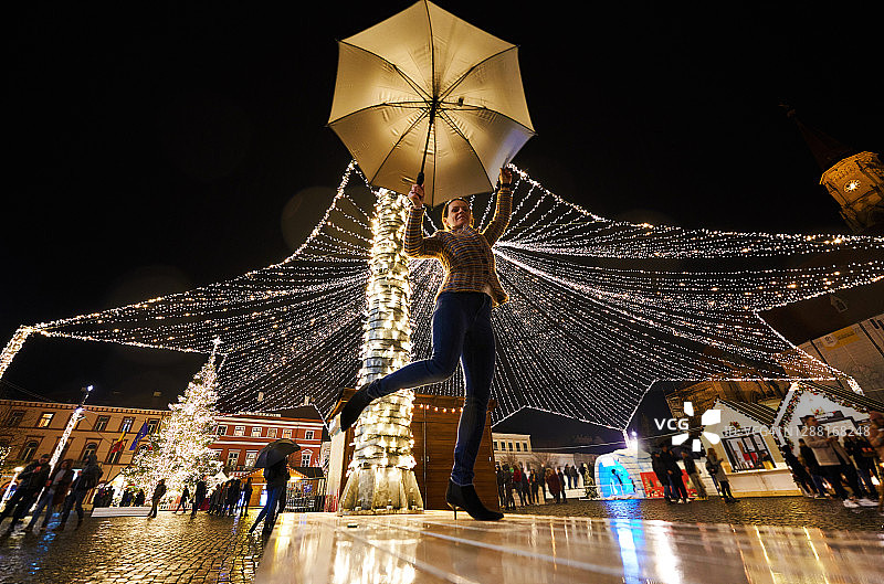 2020年圣诞节，女人撑着伞享受圣诞装饰灯。图片素材