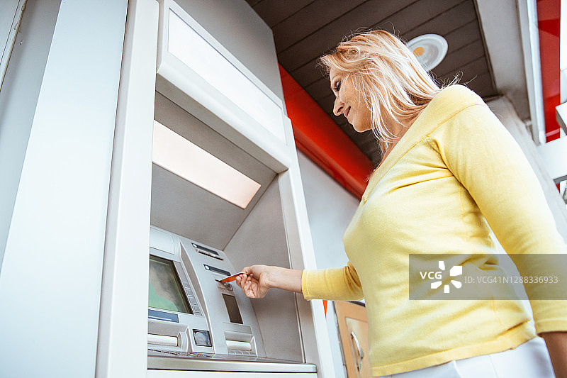 一个女人在自动取款机上查她的银行账户余额图片素材