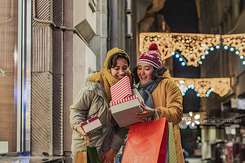 两个兴奋的女性朋友在圣诞购物图片素材