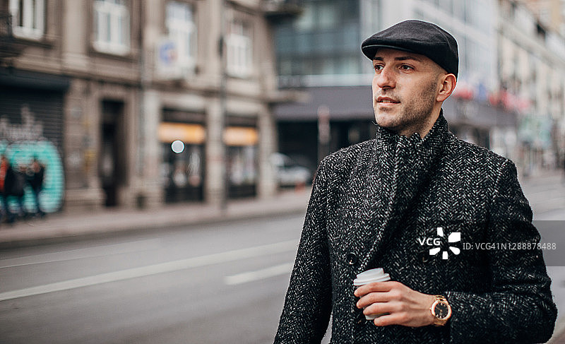 年轻人穿着暖和的衣服拿着咖啡走在城市里图片素材