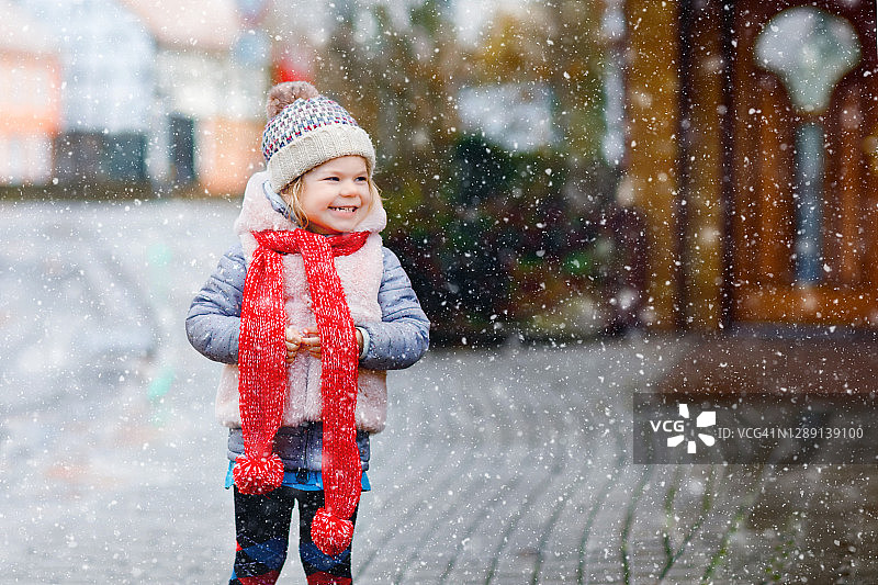 可爱可爱的小女孩穿着五颜六色的冬装玩雪，在下雪的时候在户外。和孩子们一起进行户外活动。快乐健康的孩子图片素材
