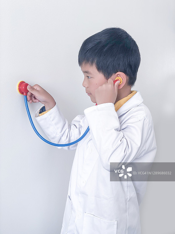 一个把听诊器放在什么东西上的男孩图片素材