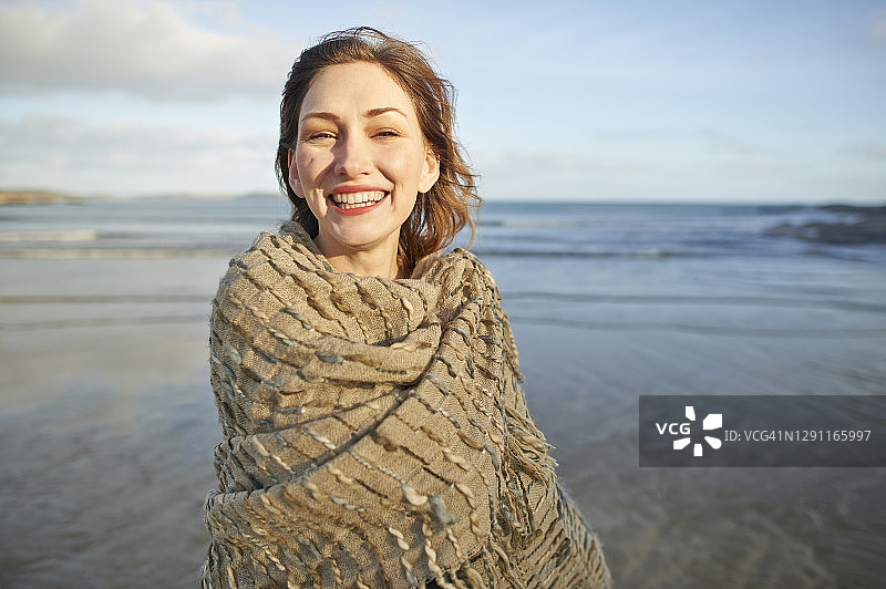 美丽无忧无虑的女人在秋天的海滩上微笑。图片素材