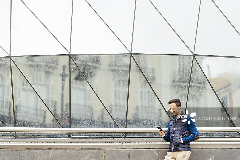一名年轻人站在大楼对面用智能手机图片素材