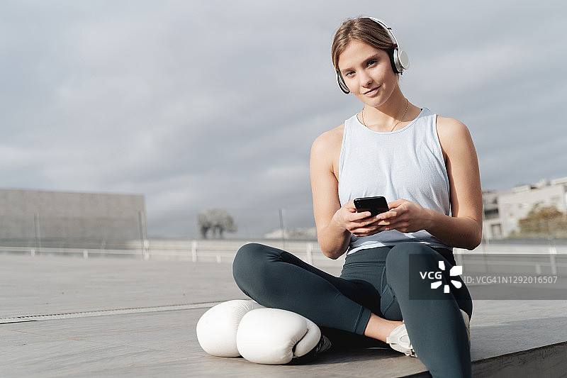 女运动员戴着耳机在户外玩手机图片素材