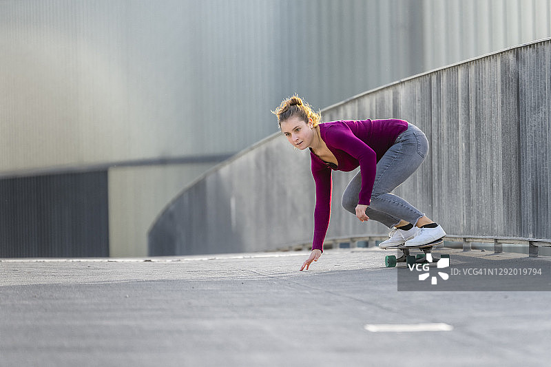 年轻女子在人行桥上玩滑板图片素材