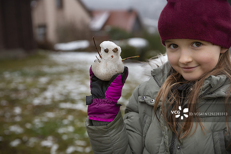 女孩(8-9)在后院，手里拿着一个小雪人图片素材